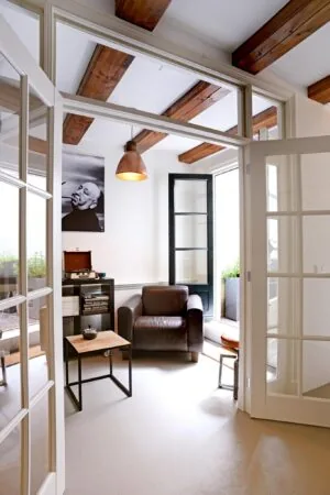 Stijlvol ingerichte zithoek met leren fauteuil, platenspeler en openstaande deuren in een woning aan de Nieuwe Kerkstraat.